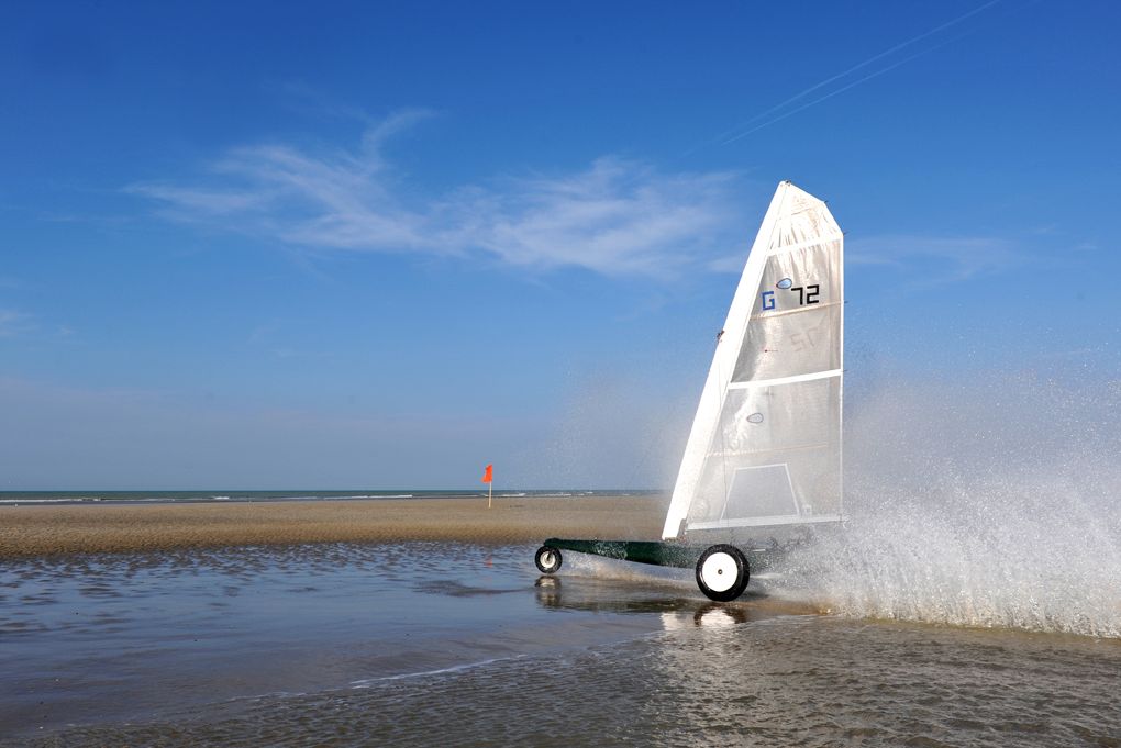 Un char à voile file sur le sable mouillé