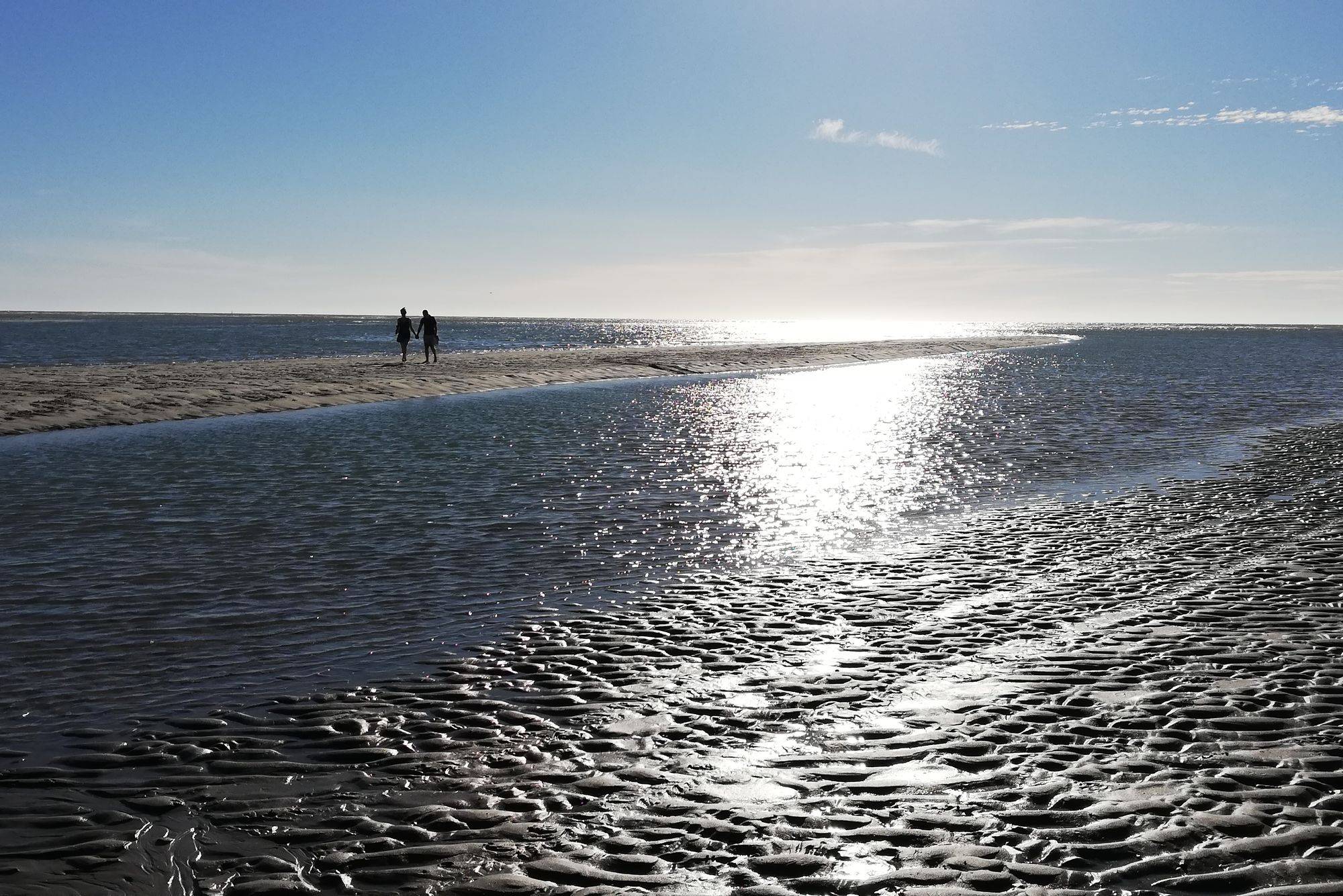 Un couple marche au bord de l’eau sur la plage de Berck à marée basse